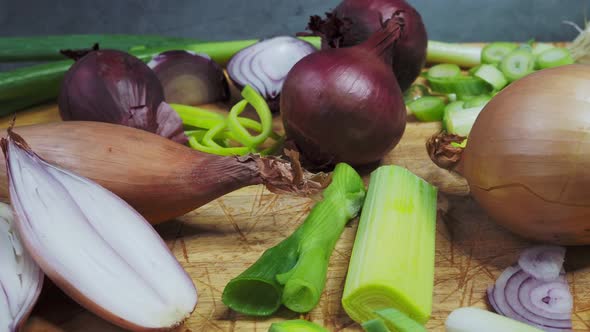 Different types of onion on wooden table. Onions, shallots, red and spring onions variety.