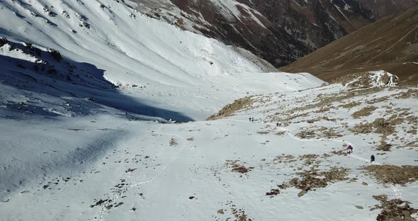 Tourists Walk Along a Snow Trail in the Mountains alt