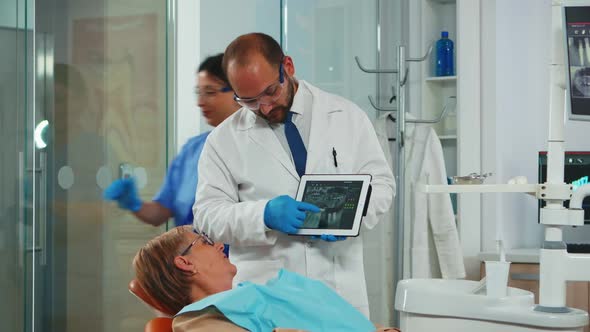 Orthodontist Using Tablet to Explain Dental Xrays to Patient alt