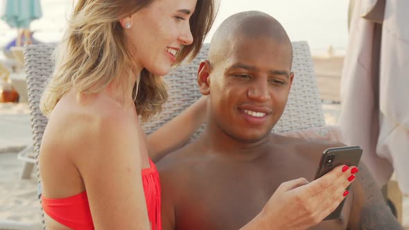Charming Multiethnic Couple Laughing Watching Something Funny on Smart Phone