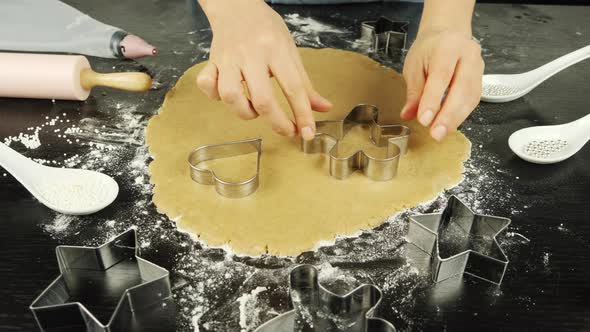 Female hand makes heart out of raw dough using baking tin alt