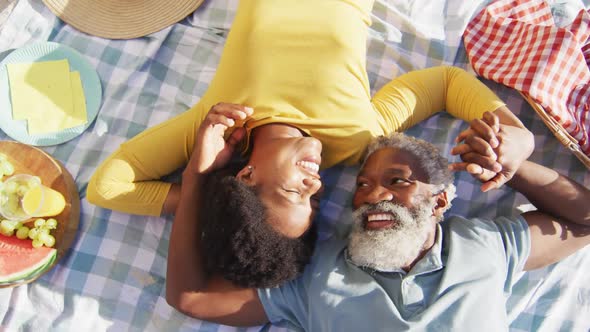 Happy african american couple having picnic on sunny beach alt