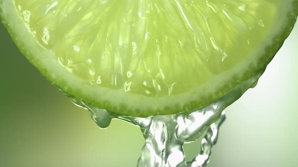 Slow Motion Macro Shot of Flowing Lime Juice From Lime Slice alt