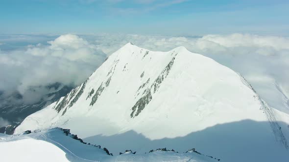 Snowy Top of Mountain in European Alps in Sunny Day. Aerial View alt