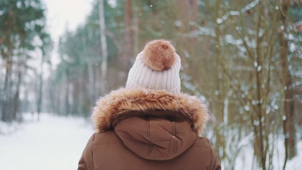 Back View of Woman in Winter Clothes Walking in the Forest alt