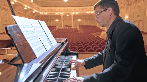 Pianist in Dark Suit Playing on a Grand Piano on Big Stage in Concert Hall