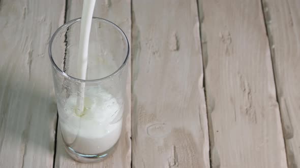 Pour Yogurt Into Glass On Vintage Wooden Boards Top View. Milk Drink In A Transparent Glass. alt