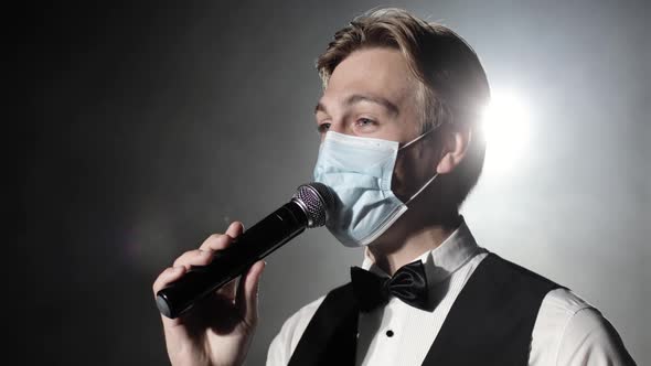 Showman Host of Event in Medical Mask Speaks at Microphone at Concert on Stage