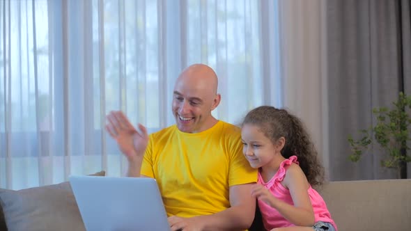 Young Serious Man Freelancer Working on a Laptop Sitting on a Sofa at Home, Using a Computer To alt