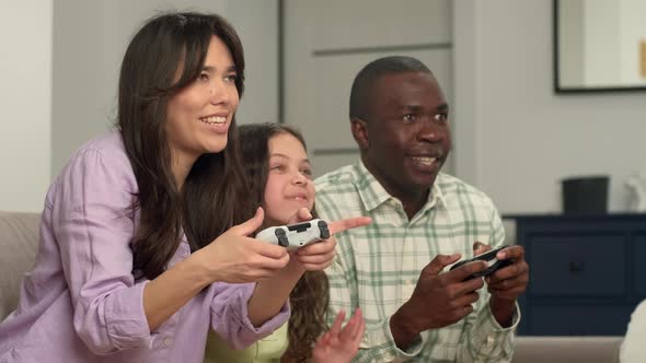 Multi Ethnic Family Playing Video Game at Home Sitting on Sofa alt
