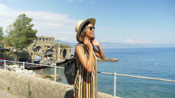 A woman looks at a Mediterranean Sea beach club in a luxury resort town in Italy, Europe alt