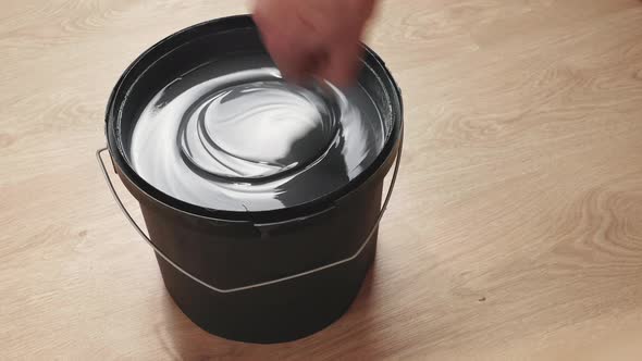 Stirring gray paint in a can. Preparing to paint the walls. alt