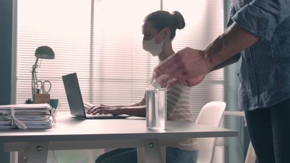 Office worker applying sanitizer on hands