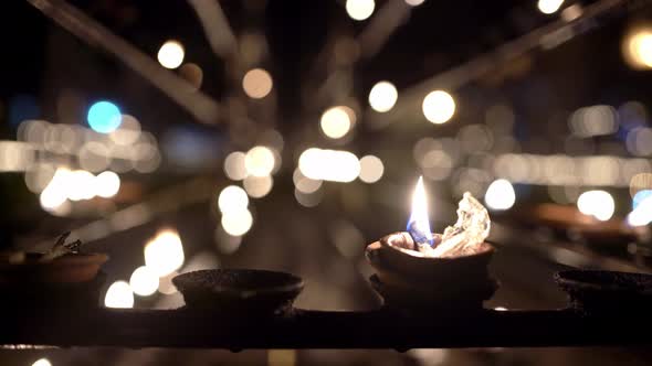 Burning Oil Candles Inside Dark Interior of Buddhist Temple