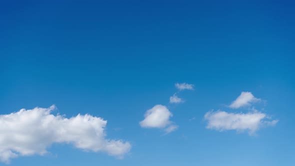 Timelapse of cumulus cloud movement against a clear blue sky alt
