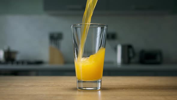 Pouring orange soda drink into glass. Close up