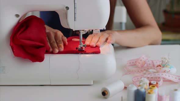 Closeup Tailor Woman Hands Sewing Red Cloth on Sewing Machine in Workplace