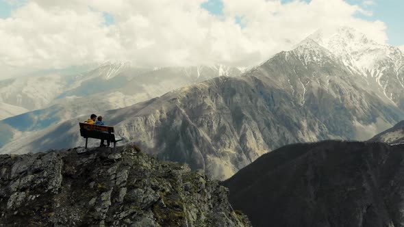 Couple Sits on Bench at Top of Mountain the Caucasus
