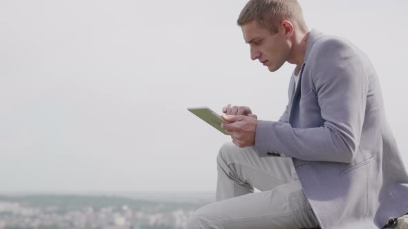 Man working on tablet outdoor, he is satisfied with his work