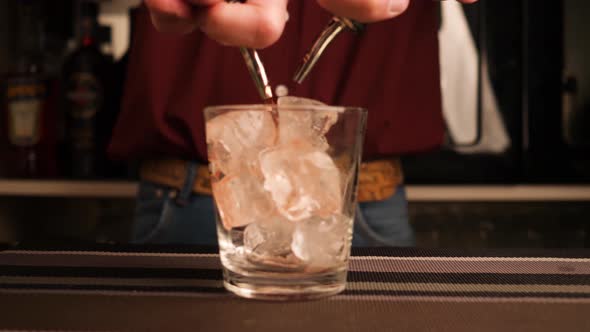 Movement in slow motion during the preparation of a cocktail using two bottles with metal Pourer.