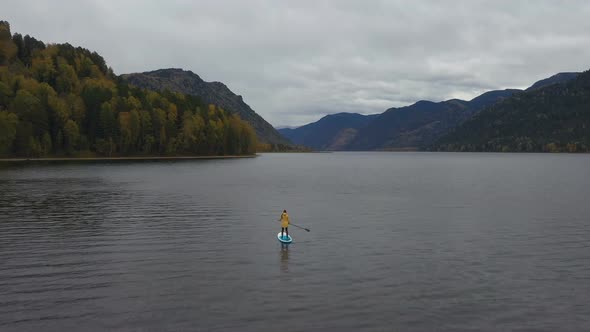 Woman Paddling on SUP Board on Teletskoye Lake in Altai Mountains, Siberia, Russia.