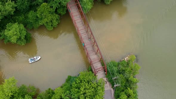 Flying above a boat traveling toward a bridge down the river alt