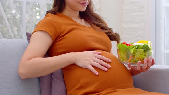Close up Pregnant Young woman eat mixture of vegetables Fresh Salad at home alt