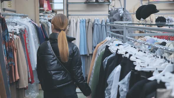 A Young Girl Choosing and Looking at Clothes in the Store alt