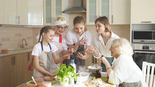 Positive Beautiful Women Use Mobile Phone While Cooking Watching Video Recipe