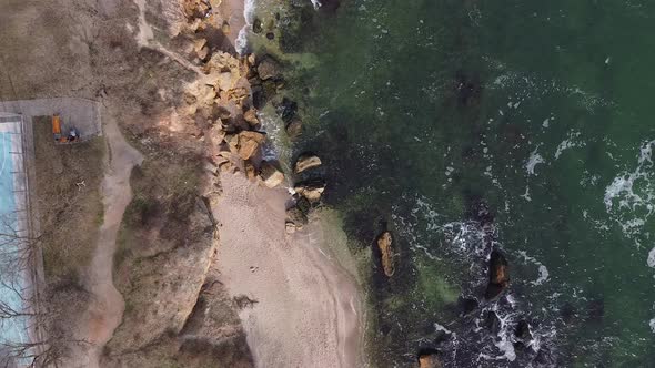 Aerial view drone flies over the ocean. The waves beat against the stones. alt