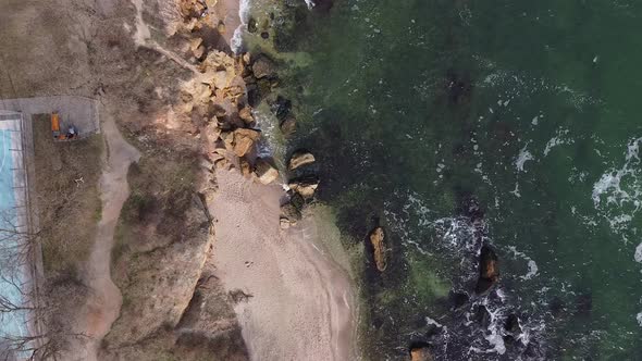 Aerial view drone flies over the ocean. The waves beat against the stones.