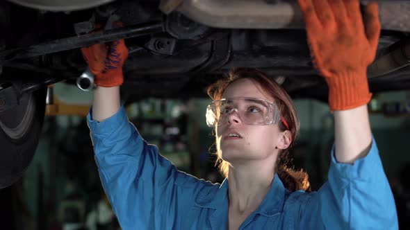 Portrait of a Female Mechanic Working Under a Vehicle in a Car Service alt