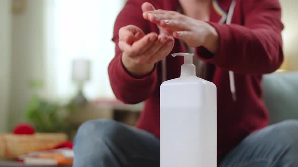 A Man Uses a Sanitizer to Disinfect the Hands at Home in the Living Room alt