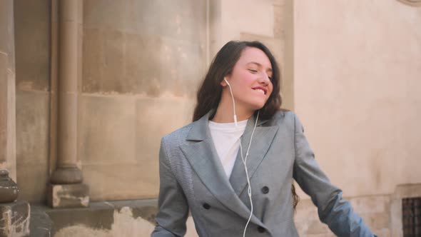 Woman in Headphones Earphones Listening to Music in the Street and Dancing alt