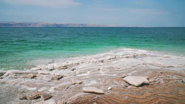 Dead Sea salt beach in Jordan, close to the Israel border. Clear blue and calm salty seaside water w alt