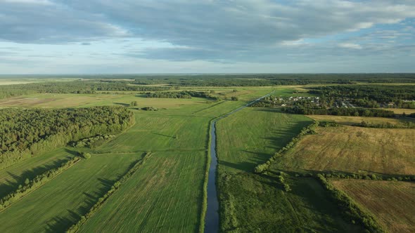 River In The Green Valley. On The Horizon Is A Village Among The Forest. alt