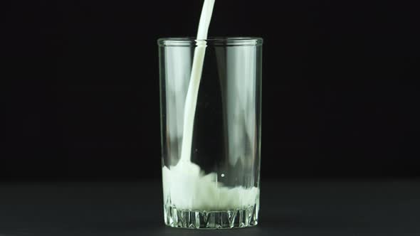 Milk Pouring Into Glass Close Up Isolated on Black Background alt