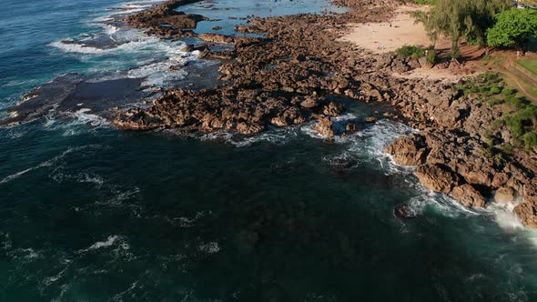 Aerial tilt up shot flying low over snorkelers and swimmers in Shark Cove along O'ahu's North Shore alt