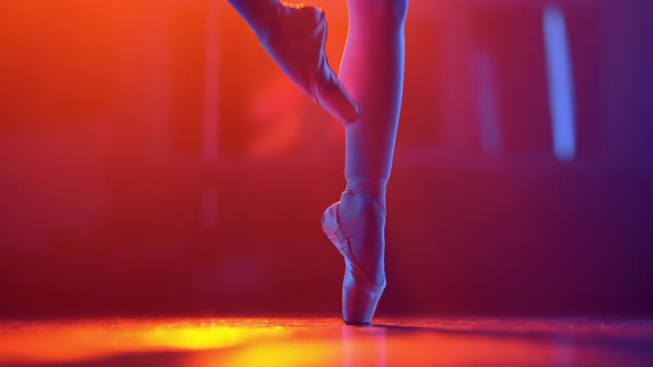 Ballet Dancer's Feet How She Practices in Pointe Shoes Exercises on Colorful Neon Spotlight alt
