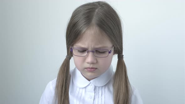 Portrait of Sad 9 Years Old School Girl in Glasses and Uniform on Gray Background alt