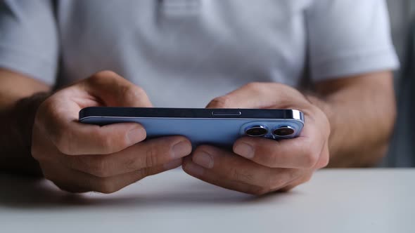 Man playing mobile game app on trendy new smart phone device with three cameras alt