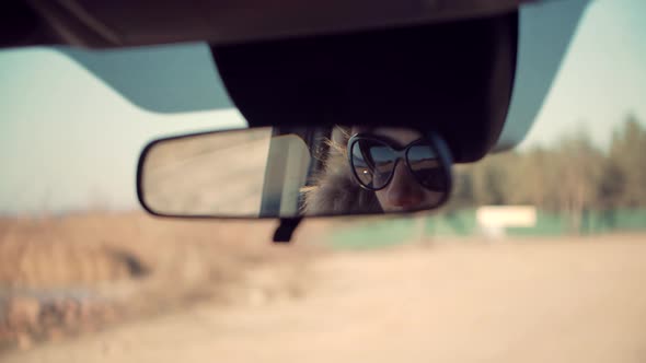 Woman Look On Car Mirror Before Driving. Girl In Sunglasses Reflected In Rearview Mirror. alt