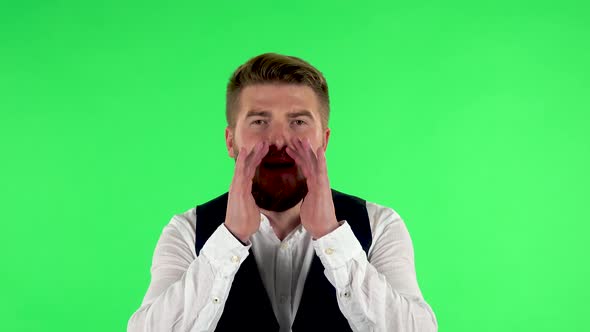 Man Screams Calling Someone on a Green Screen at Studio. alt