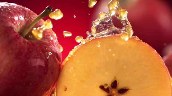 Slow Motion Shot of Red Apple Juice Splashing Through Apple Slices alt
