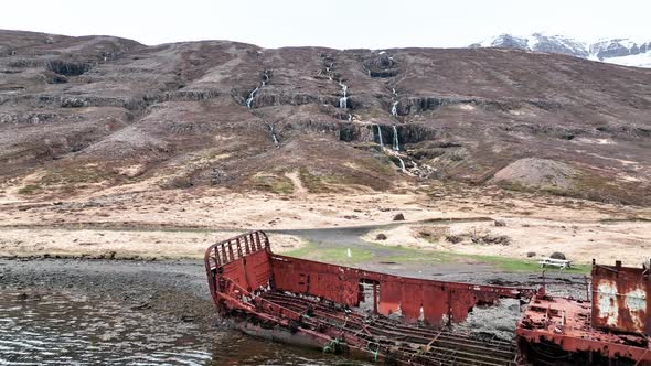 Ruins Of WWII US Navy LCM Ship In Mjoifjordur, East Iceland. Drone Pullback Shot alt