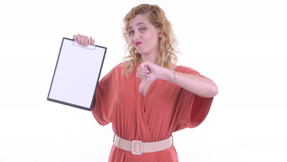 Stressed Blonde Businesswoman Showing Clipboard and Giving Thumbs Down alt