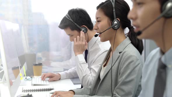 Asian businesswoman wearing headphone working in call center office with team