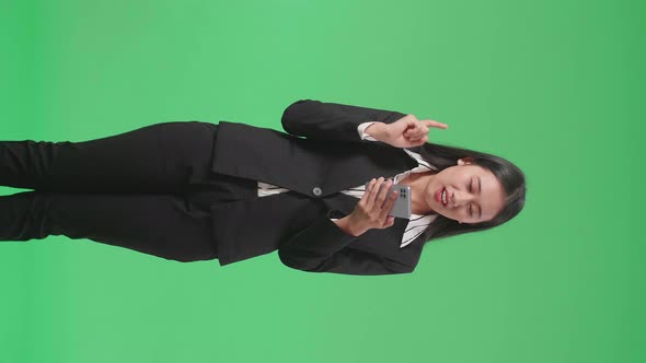 Asian Business Woman Raising Index Finger Using Mobile Phone In The Green Screen alt