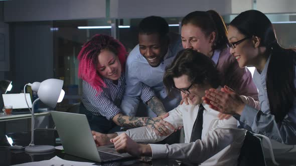 Happy Multiethnic Team Congratulate Coworker with Success in Dark Office alt