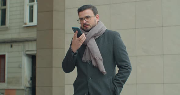 Businessman Use Smartphone To Send Voice Messages Outdoors at Downtown. Smiling Young Business Man alt